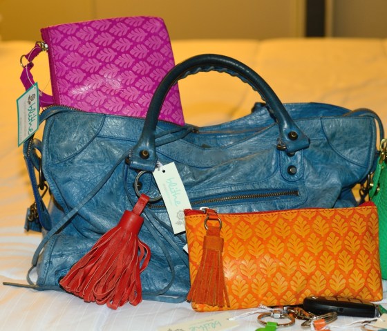 {Fuchsia Neem Clutch, small Orange Neem Clutch & Red Tassel Key Ring shown on Blue Balenciaga Bag}